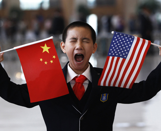 A boy who is waiting to greet U.S. Secretary of State Clinton at the National Museum makes a face while holding the U.S. and Chinese flags in Beijing